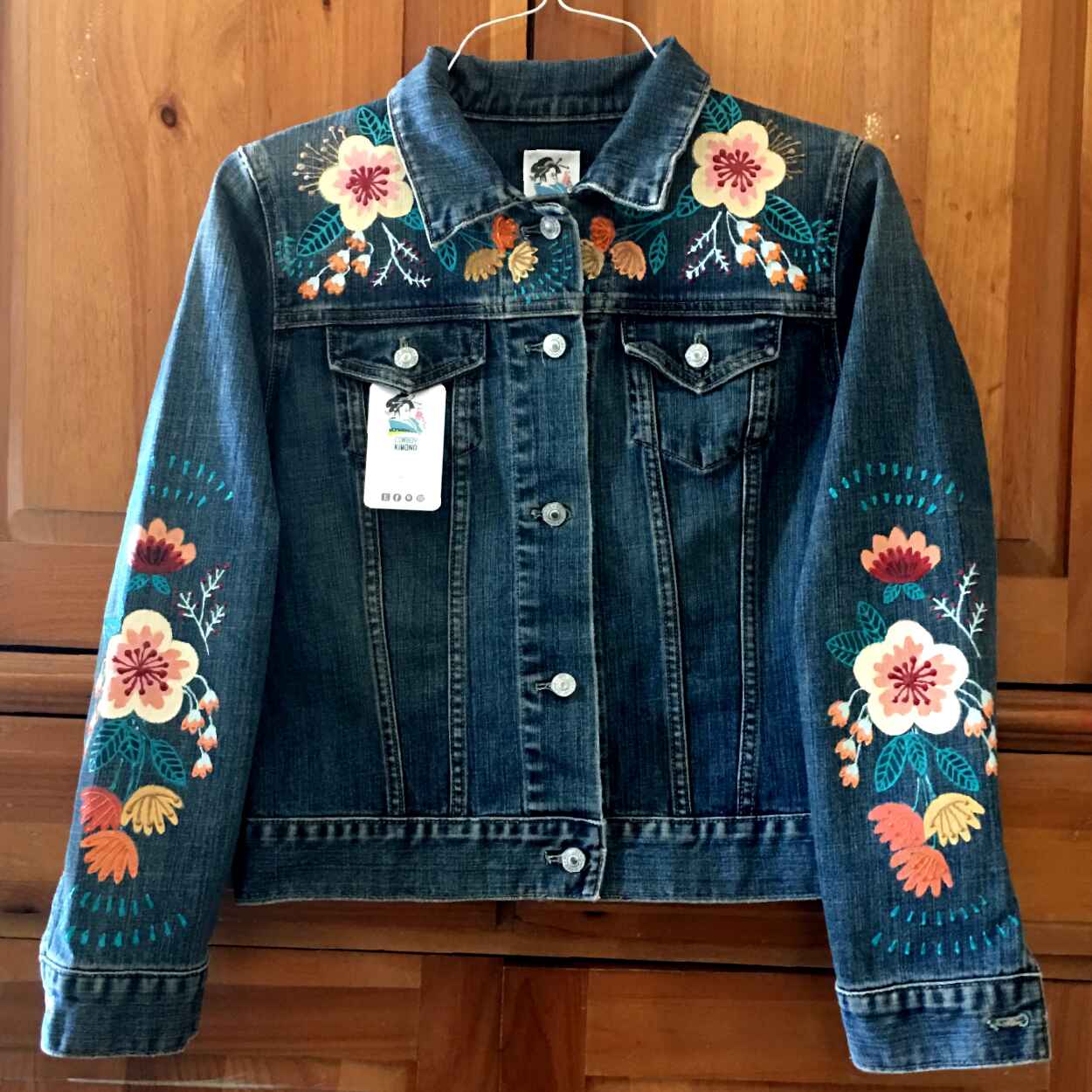 Denim Jacket with bright flowers painted on shoulders and sleves.