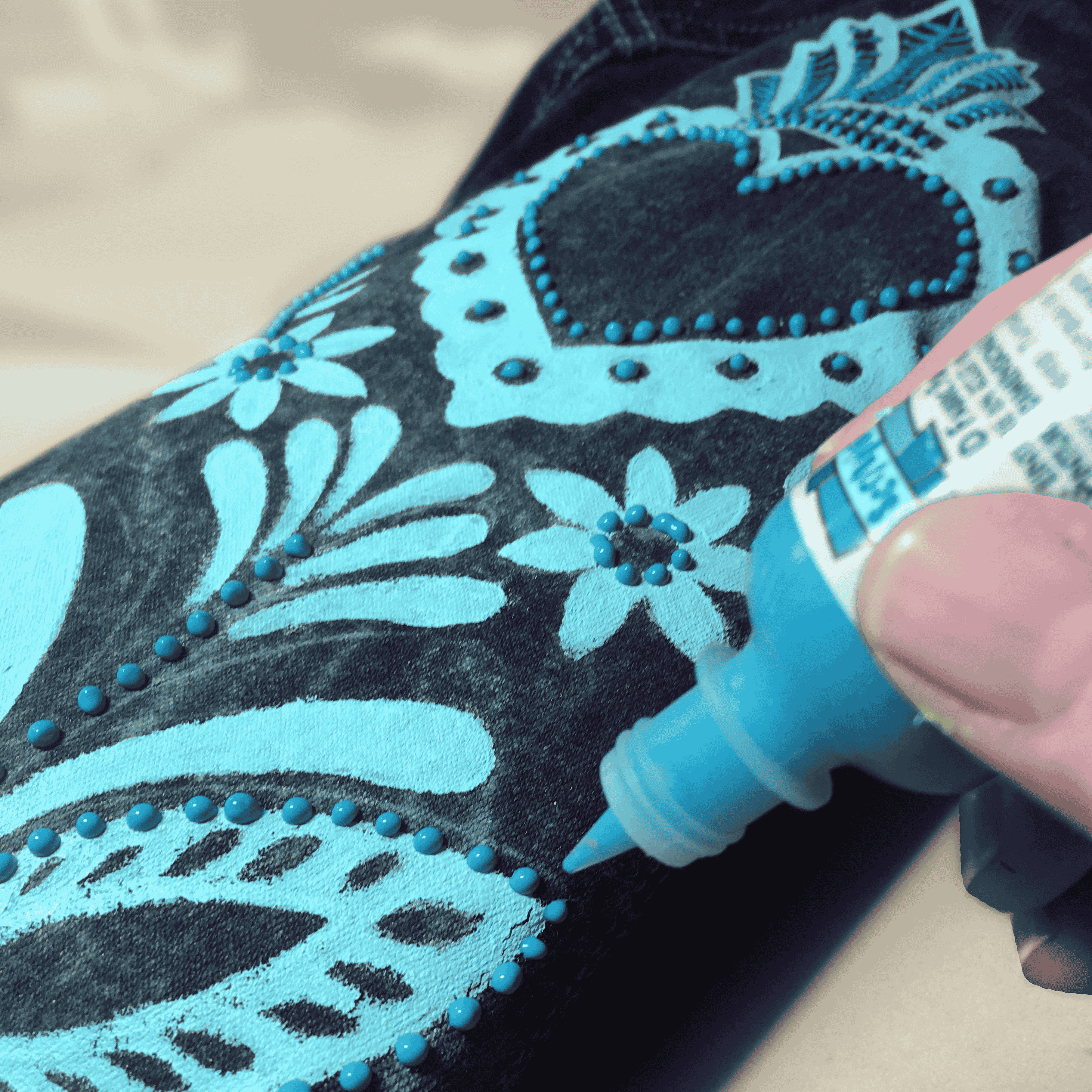 A hand applying fabric paint to a denim jacket